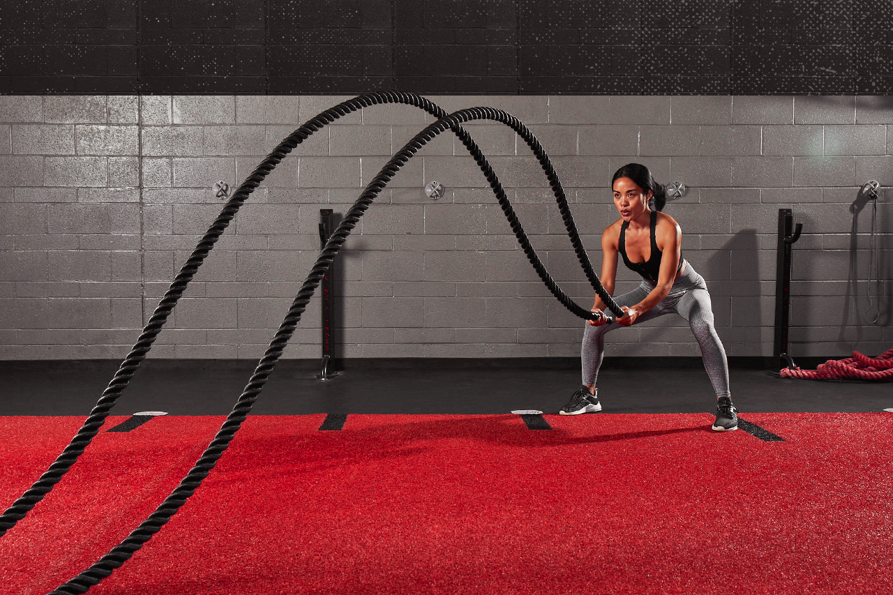 Woman working out with battle ropes in UFC GYM